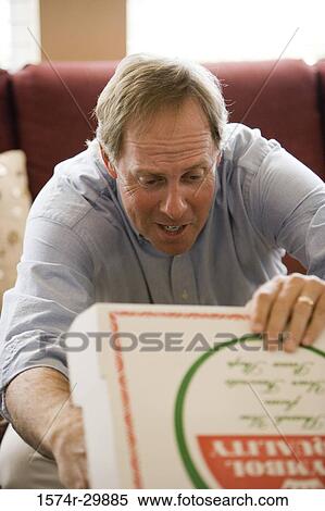 Stock Photography - Mature man removing a pizza from a box. Fotosearch