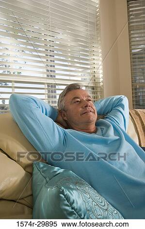 Stock Photography - Mature man sitting on a couch. Fotosearch