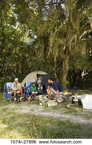 Mature man sitting with his son and friend by tent at forest View Large Photo Image Stock Photograph - Mature man sitting with his son and friend by tent at forest. Fotosearch