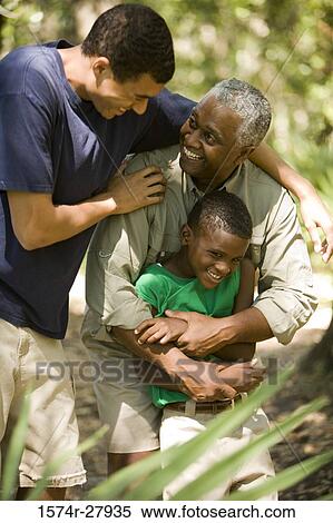 Stock Photography - Mature man with his son and friend smiling at forest. Fotosearch