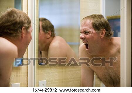 Stock Image - Mature man yawning in front of a bathroom mirror. Fotosearch