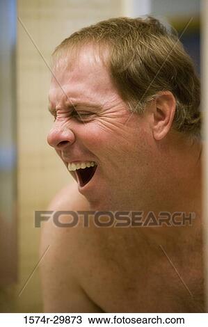 Mature man yawning in front of a bathroom mirror View Large Photo Image Stock Image - Mature man yawning in front of a bathroom mirror. Fotosearch