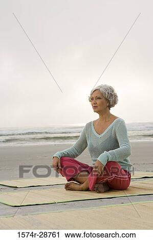 Mature woman exercising on a mat at the beach View Large Photo Image Stock Image - Mature woman exercising on a mat at the beach. Fotosearch