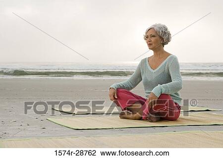 Mature woman exercising on a mat at the beach View Large Photo Image Stock Image - Mature woman exercising on a mat at the beach. Fotosearch