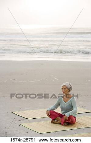 Mature woman exercising on a mat at the beach View Large Photo Image Stock Image - Mature woman exercising on a mat at the beach. Fotosearch