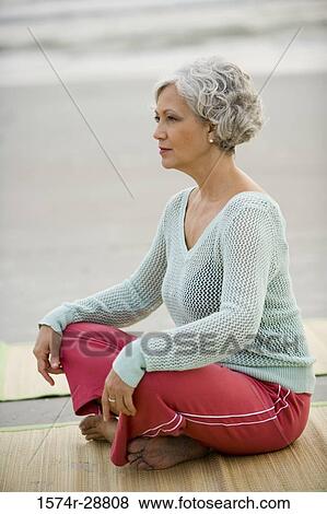 Mature woman exercising on a mat at the beach View Large Photo Image Stock Photo - Mature woman exercising on a mat at the beach. Fotosearch