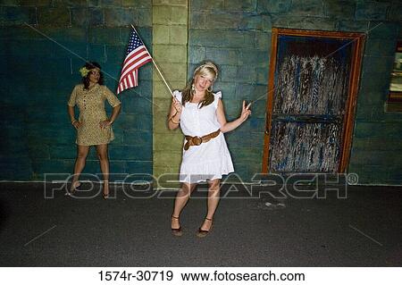 Stock Photo - Mature woman holding a American flag and gesturing while daughter behind. Fotosearch