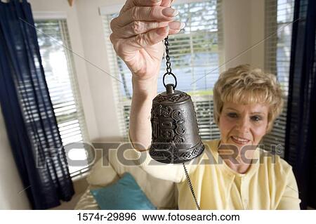 Mature woman holding up a traditional bell View Large Photo Image Stock Photograph - Mature woman holding up a traditional bell. Fotosearch