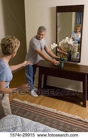 Mature woman pointing at mature man holding a houseplant View Large Photo Image Stock Photography - Mature woman pointing at mature man holding a houseplant. Fotosearch