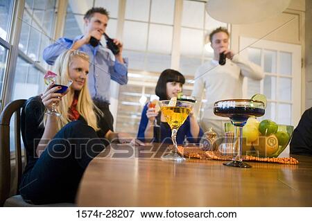 Stock Photo - Men and women enjoying drinks in the dining room. Fotosearch