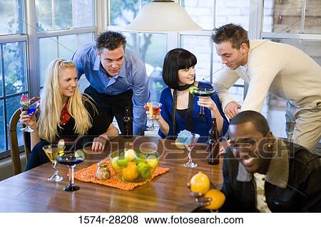 Stock Photo - Men and women enjoying drinks in the dining room. Fotosearch