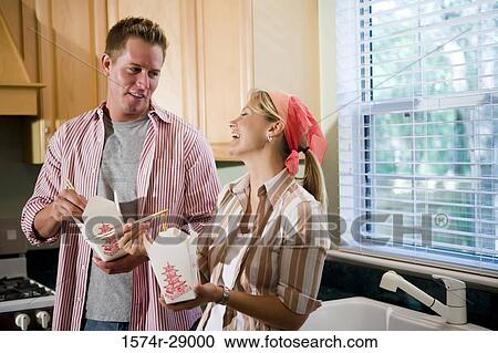 Mid adult couple eating fast food by kitchen sink in the kitchen View Large Photo Image Stock Image - Mid adult couple eating fast food by kitchen sink in the kitchen. Fotosearch