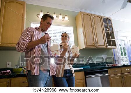 Mid adult couple eating fast food in the kitchen View Large Photo Image Stock Photo - Mid adult couple eating fast food in the kitchen. Fotosearch