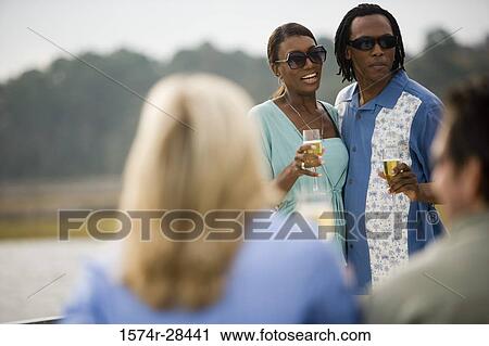 Mid adult couple standing with glass of champagne View Large Photo Image Stock Image - Mid adult couple standing with glass of champagne. Fotosearch