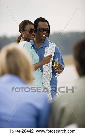 Mid adult couple standing with glass of champagne View Large Photo Image Stock Image - Mid adult couple standing with glass of champagne. Fotosearch