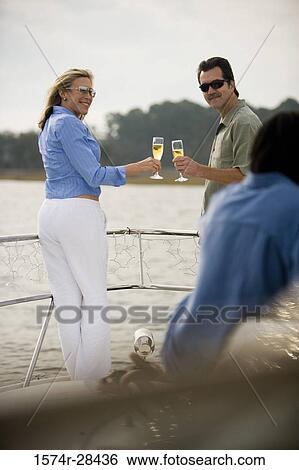 Stock Photograph - Mid adult couple standing with glass of champagne. Fotosearch