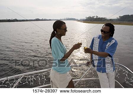 Mid adult couple toasting champagne on the deck of a boat View Large Photo Image Stock Photo - Mid adult couple toasting champagne on the deck of a boat. Fotosearch