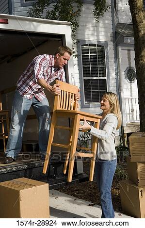 Mid adult couple unloading chairs and cardboard boxes from the moving van View Large Photo Image Picture - Mid adult couple unloading chairs and cardboard boxes from the moving van. Fotosearch