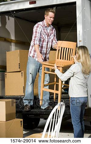 Mid adult couple unloading chairs and cardboard boxes from a moving van View Large Photo Image Picture - Mid adult couple unloading chairs and cardboard boxes from a moving van. Fotosearch
