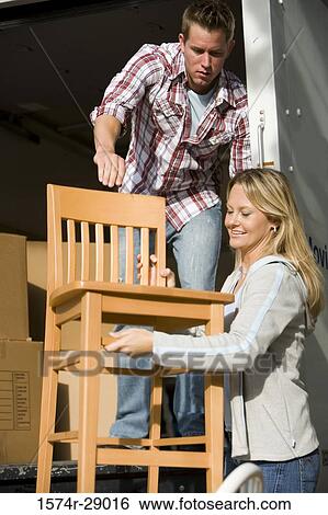 Mid adult couple unloading chairs and cardboard boxes from a moving van View Large Photo Image Stock Photograph - Mid adult couple unloading chairs and cardboard boxes from a moving van. Fotosearch