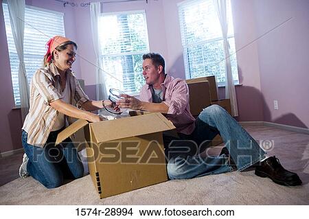 Mid adult couple unpacking cardboard box in a house View Large Photo Image Picture - Mid adult couple unpacking cardboard box in a house. Fotosearch