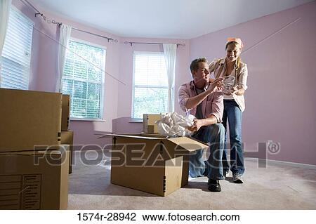 Mid adult couple unpacking cardboard box in a house View Large Photo Image Stock Image - Mid adult couple unpacking cardboard box in a house. Fotosearch