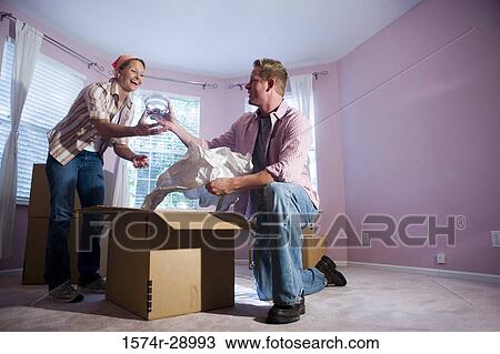 Mid adult couple unpacking cardboard box in a house View Large Photo Image Stock Image - Mid adult couple unpacking cardboard box in a house. Fotosearch