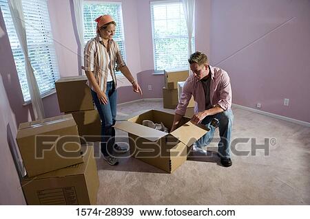 Mid adult couple unpacking cardboard box in a house View Large Photo Image Stock Photo - Mid adult couple unpacking cardboard box in a house. Fotosearch