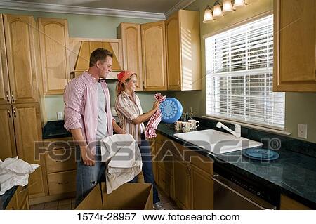 Mid adult couple unpacking cardboard box in the kitchen View Large Photo Image Stock Photo - Mid adult couple unpacking cardboard box in the kitchen. Fotosearch