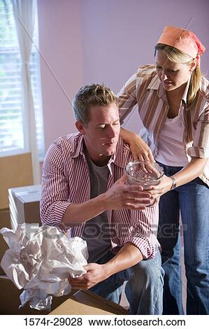 Mid adult couple unpacking cardboard box in a house View Large Photo Image Stock Photo - Mid adult couple unpacking cardboard box in a house. Fotosearch