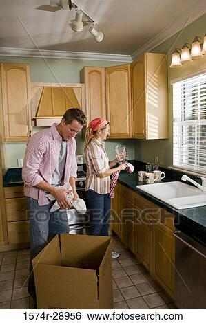 Mid adult couple unpacking cardboard box in the kitchen View Large Photo Image Stock Photograph - Mid adult couple unpacking cardboard box in the kitchen. Fotosearch