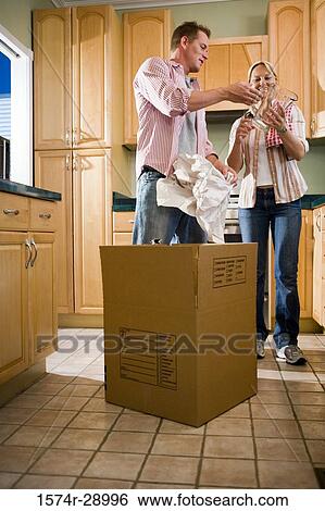 Mid adult couple unpacking cardboard box and looking at a jar in the kitchen View Large Photo Image Stock Photograph - Mid adult couple unpacking cardboard box and looking at a jar in the kitchen. Fotosearch