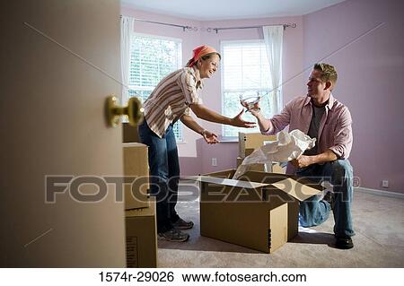 Mid adult couple unpacking cardboard box in a house View Large Photo Image Stock Photograph - Mid adult couple unpacking cardboard box in a house. Fotosearch