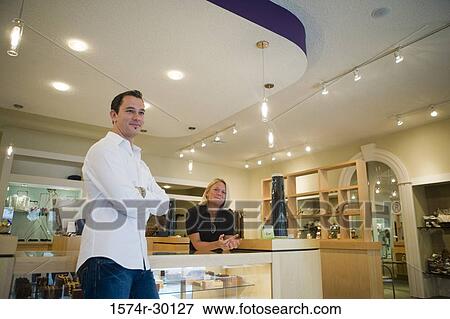 Mid adult man and woman standing in a store View Large Photo Image Stock Photo - Mid adult man and woman standing in a store. Fotosearch