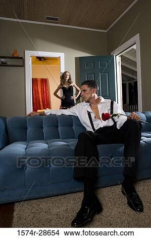 Picture - Mid adult man holding a rose while a young prostitute standing by door. Fotosearch