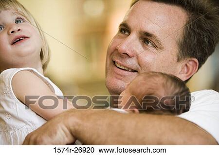 Mid adult man holding his baby and daughter View Large Photo Image Stock Image - Mid adult man holding his baby and daughter. Fotosearch