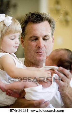 Stock Image - Mid adult man holding his baby and daughter. Fotosearch