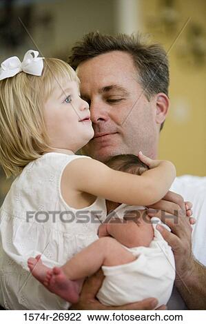 Stock Image - Mid adult man holding his baby and daughter. Fotosearch