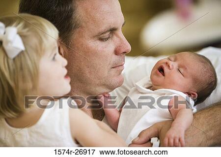 Stock Photo - Mid adult man holding his baby and daughter. Fotosearch
