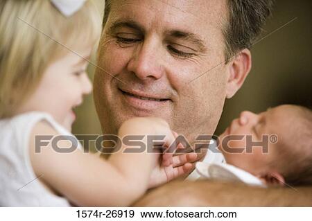 Mid adult man holding his baby and daughter View Large Photo Image Stock Photo - Mid adult man holding his baby and daughter. Fotosearch
