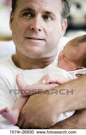 Mid adult man holding his baby View Large Photo Image Stock Image - Mid adult man holding his baby. Fotosearch