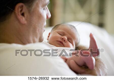 Mid adult man holding his baby View Large Photo Image Stock Image - Mid adult man holding his baby. Fotosearch