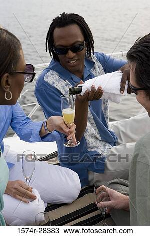 Mid adult man pouring champagne to woman's glass View Large Photo Image Stock Image - Mid adult man pouring champagne to woman's glass. Fotosearch