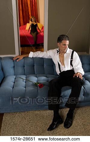 Mid adult man sitting on a sofa with a young prostitute in the background View Large Photo Image Stock Image - Mid adult man sitting on a sofa with a young prostitute in the background. Fotosearch
