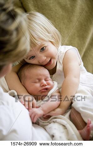Stock Photo - Mid adult woman holding her baby and daughter. Fotosearch