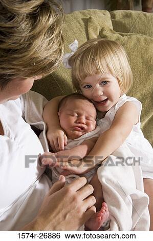 Mid adult woman holding her baby and daughter View Large Photo Image Stock Photograph - Mid adult woman holding her baby and daughter. Fotosearch
