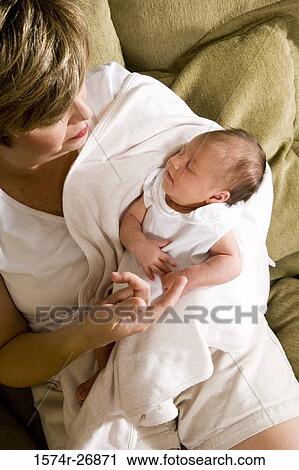 Stock Image - Mid adult woman holding her baby in hands. Fotosearch