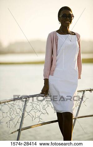 Mid adult woman in sunglasses standing by railing View Large Photo Image Picture - Mid adult woman in sunglasses standing by railing. Fotosearch