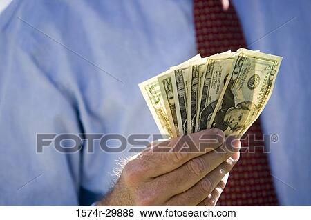 Midsection of a businessman holding American dollars View Large Photo Image Stock Photo - Midsection of a businessman holding American dollars. Fotosearch