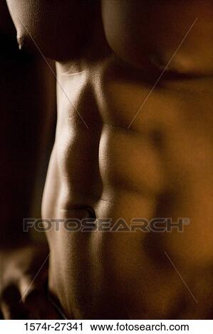 Stock Image - Midsection of a shirtless man after working out in the gym. Fotosearch